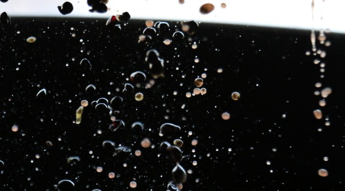 Pinot Noir grapes in mid air as they go through the de-stalking process.